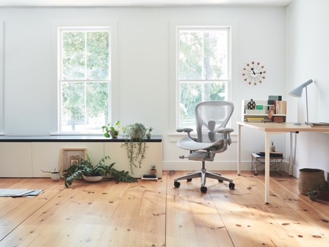 Aeron Chair in mineral seen from the front next to an Everywhere Table in a brightly lit home setting. 